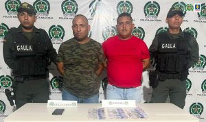 Dos uniformados del Gaula custodian a los procesados quienes están esposados. 