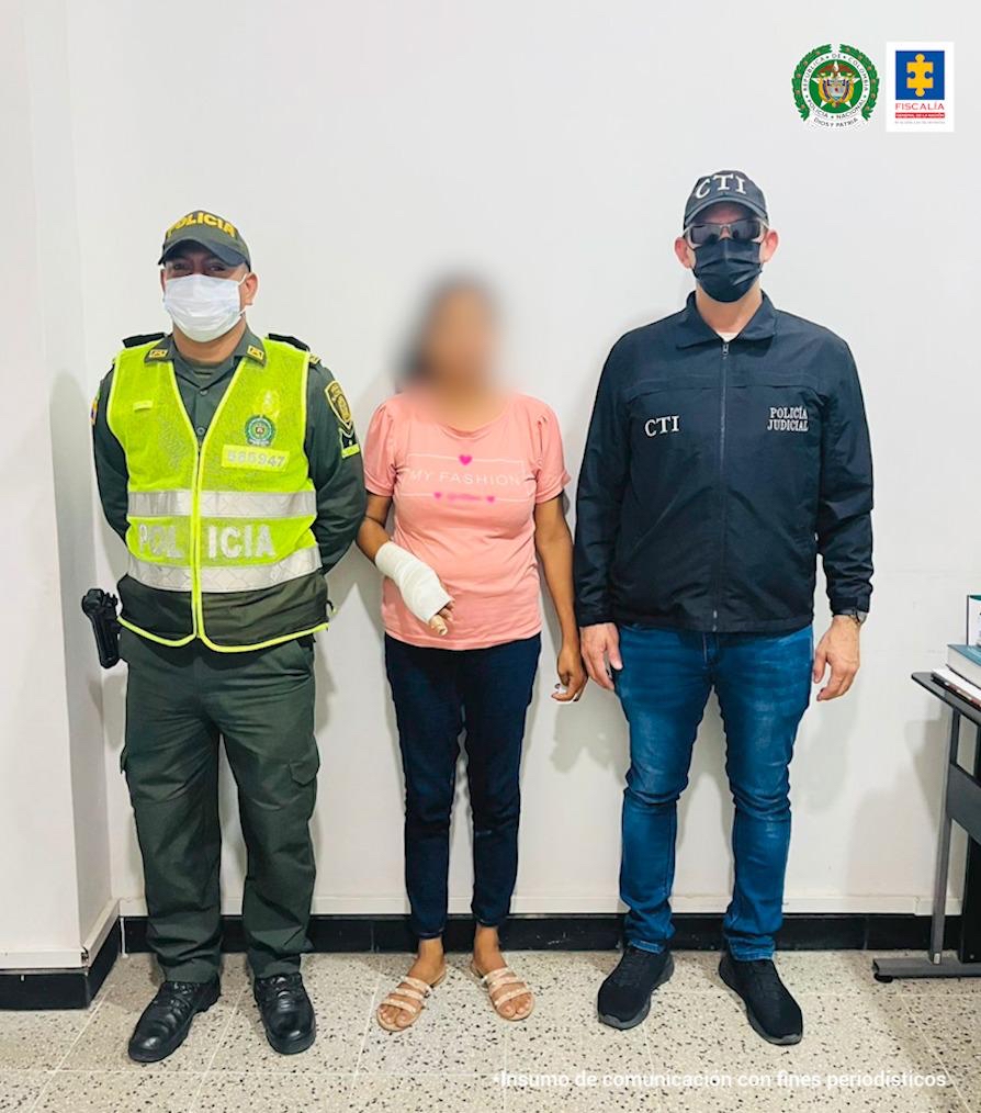 En la fotografía está una mujer, con una blusa de color rosado. La escoltan dos funcionarios de la Policía y el CTI, respectivamente.