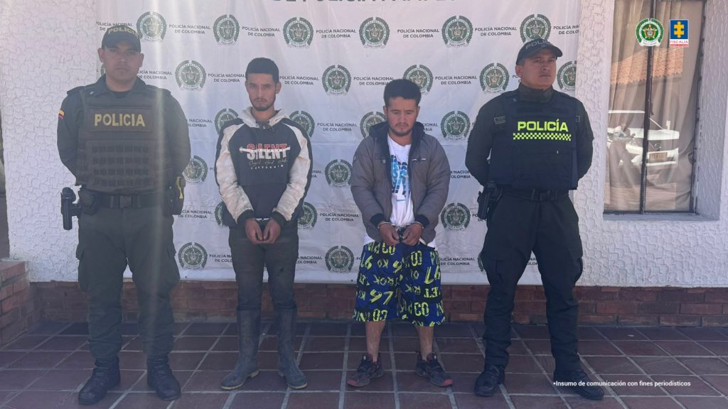 Se visualiza a los dos capturados junto a uniformados de la Policía Nacional. Detrás de ellos el banner que identifica a la Policía Nacional.