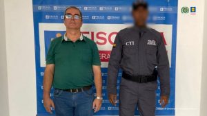 En la fotografía se aprecia de pie a Iván Darío Villegas Castañeda. Viste camisa de manga corta de color verde, jean azul y zapatos negros. A su izquierda hay un servidor del CTI de la Fiscalía. Detrás de ellos hay un pendón institucional de la Fiscalía.
