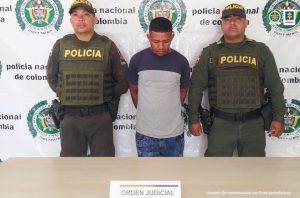 Fiscal Martha Mancera, Martha Mancera, Fiscal Mancera En la imagen se ve una persona de suéter gris con azul, entre dos uniformados de la Policía.