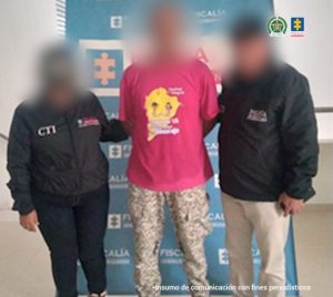 En la imagen aparece una persona detenida, de suéter fucsia, entre dos uniformados del CTI.