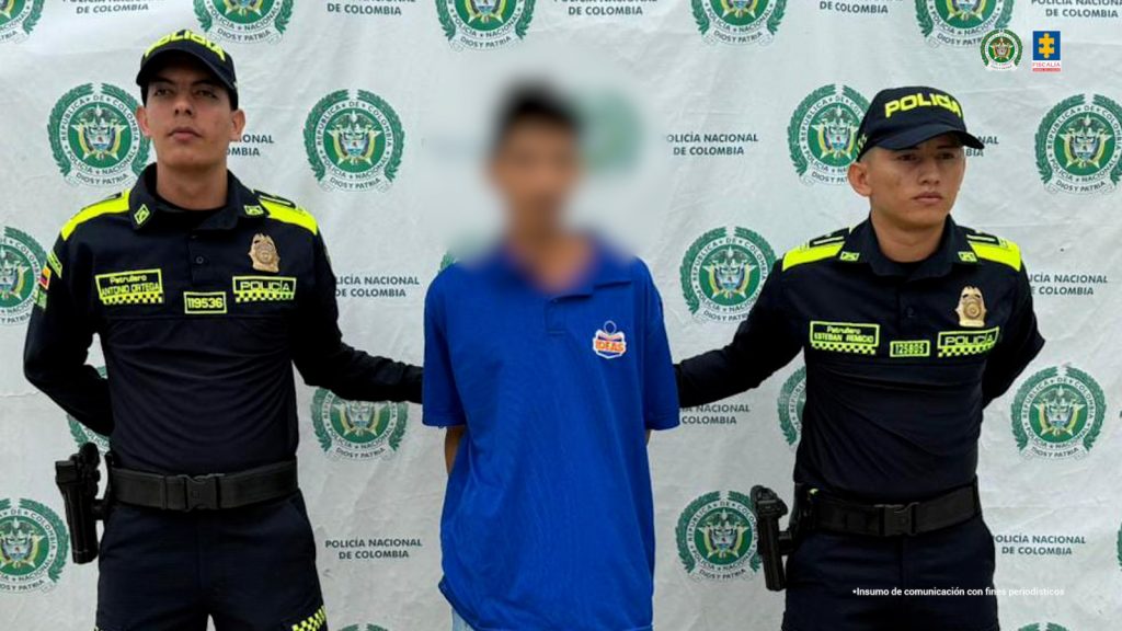 En la imagen aparece una persona de camiseta azul entre dos uniformados de la Policía Nacional.