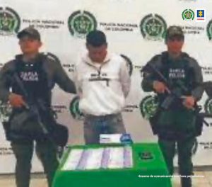 en la foto se aprecia al hoy asegurado siendo custodiado por dos policías y el el dinero que se le encontró a la hora de la captura.