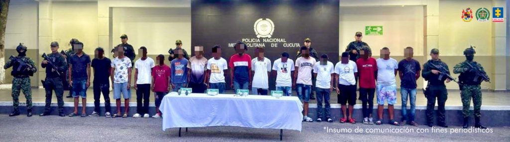 Se visualiza a los 17 capturados junto a uniformados del Gaula de la Policía y Ejército Nacional. Detrás de ellos el banner que identifica a la Policía Nacional.