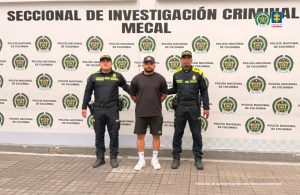 En la fotografía aparece de pie y con los brazos atrás Jaider Viloria Mendoza. Usa gorra de color negro con un aplique de color amarillo mostaza en la parte frontal. Viste con camita de mangas cortas y pantaloneta de color negro; medias y zapatillas de color blanco. En sus extremos hay uniformados de la Policía Nacional. Detrás de ellos hay un pendón institucional de la Policía.