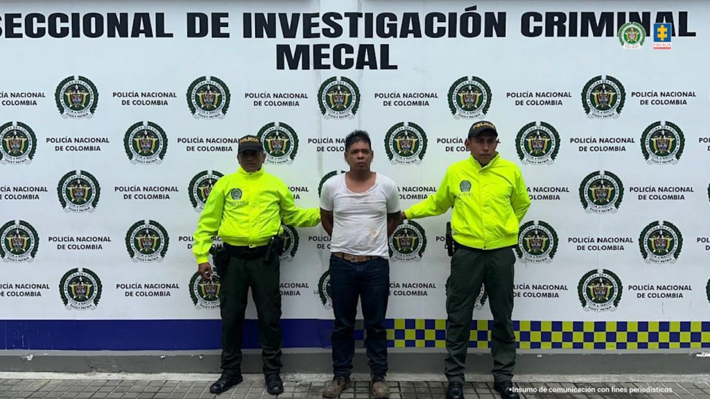 En la fotografía se aprecia de pie, con los brazos atrás a Jaider Yesid Estrella Vele. Viste camiseta de manga corta de color blanco; pantalón negro y zapatos cafés. A sus extremos hay uniformados de la Policía Nacional. Detrás de ellos hay un pendón institucional de la Policía.