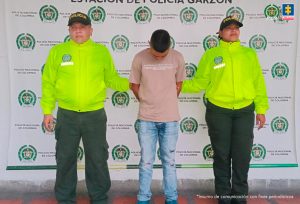 El procesado se encuentra esposado y en custodia por uniformados de la Policía Nacional. Detrás suyo un backing de la Policía.