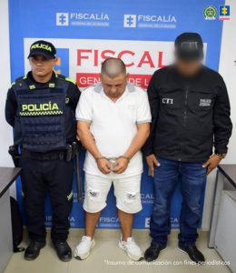 En la fotografía se aprecia de pie, con los brazos adelante, esposado y la cabeza agachada a Jaime Andrés Arias Sánchez. Viste camisa de manga corta de color blanca; bermudas blancas y zapatillas blancas. A su lado izquierdo hay un servidor del CTI de la Fiscalía y a su derecha un uniformado de la Policía Nacional. Detrás de ellos hay un pendón institucional de la Fiscalía.