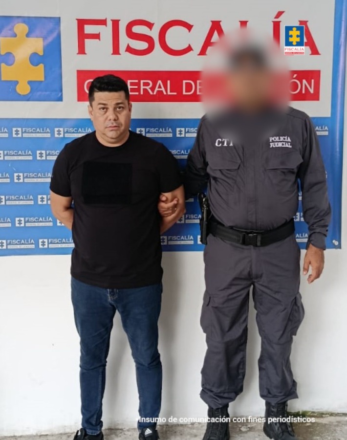 En la imagen aparece una persona de suéter negro junto a un uniformado del CTI de la Fiscalía.