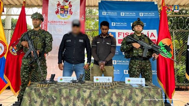 Se visualiza al capturado junto a uniformados del Ejército Nacional. Frente a ellos una mesa con los elementos incautados.