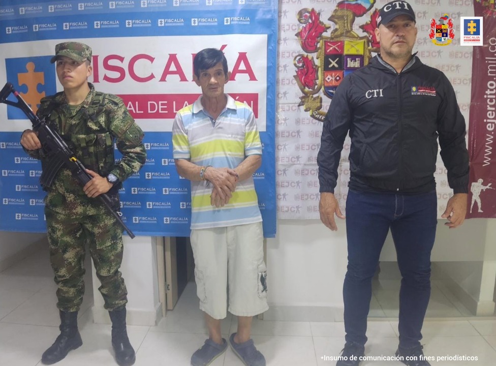 En las fotografía aparece un capturado, junto a personal de CTI y Ejército Nacional. En la parte posterior de la imagen se ven banners de Ejército Nacional y la Fiscalía General de la Nación.  