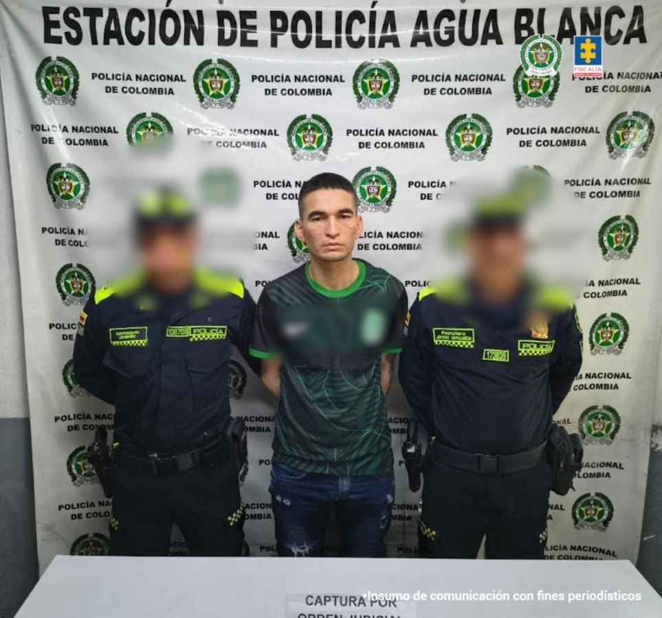 En la foto aparece el capturado de frente y custodiado por dos uniformados de la Policía Nacional. En la foto aparece un backing de la Policía Nacional.