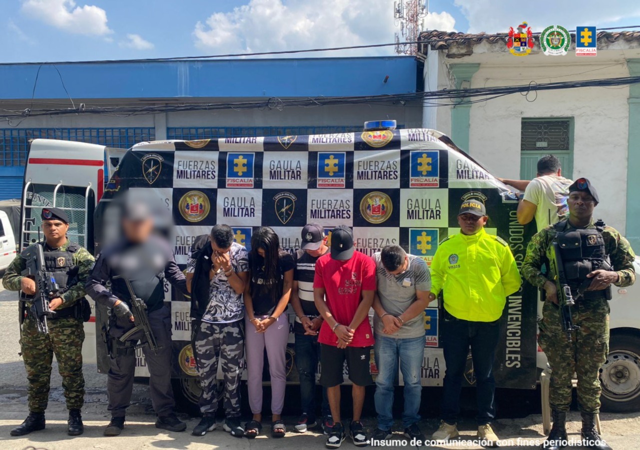 En la fotografía, tomada en exteriores, se aprecia a los 4 presuntos implicados en hurtos a residencias y locales comerciales. Igualmente, hay una mujer. Todos tienen la cabeza agachada, dos de ellos usan gorra de olor negro y están esposados. Al extremo derecho de ellos hay un servidor del CTI de la Fiscalía y del Ejército. Al extremo izquierdo hay un uniformado de la Policía y del Ejército. detrás de ellos hay un pendón interinstitucional con los logos de Fiscalía, Ejército y las palabras 'Gaula Militar´.