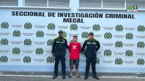 En la fotografía aparece de pie y con los brazos atrás Jean Pool Bejarano Campo. Viste con buso de color rojo y estampado blanco en el pecho; bermuda negra con algunas aplicaciones de color rojo, así como pantuflas de color negro. En sus extremos hay uniformados de la Policía Nacional. Detrás de ellos hay un pendón institucional de la Policía.