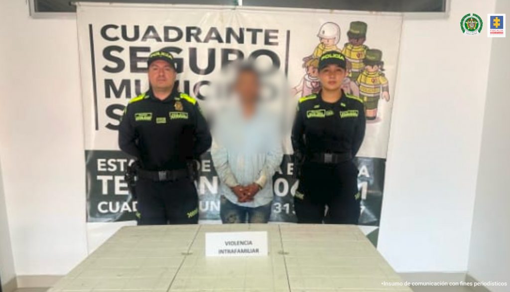 En la fotografía se aprecia de pie y con los brazos adelante a Jefferson Andrés Velasco Moreno. Viste camisa azul claro, de manga larga y jean azul. A lado y lado de él hay uniformados de la Policía Nacional. Delante de ellos hay una mesa blanca y sobre ella hay un letrero que dice: ‘Violencia intrafamiliar’. Detrás de ellos hay un pendón institucional de la Policía.