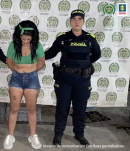 caturada de frente custodiada por una policía. Detrás bannaer de la Policía Nacional.