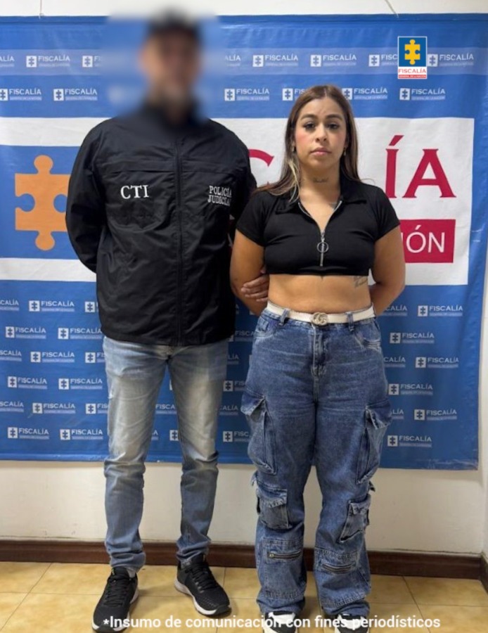 Jessica Britney González Motato acompañada en la foto por un funcionario del CTI y detrás el pendón con logos de la Fiscalía.