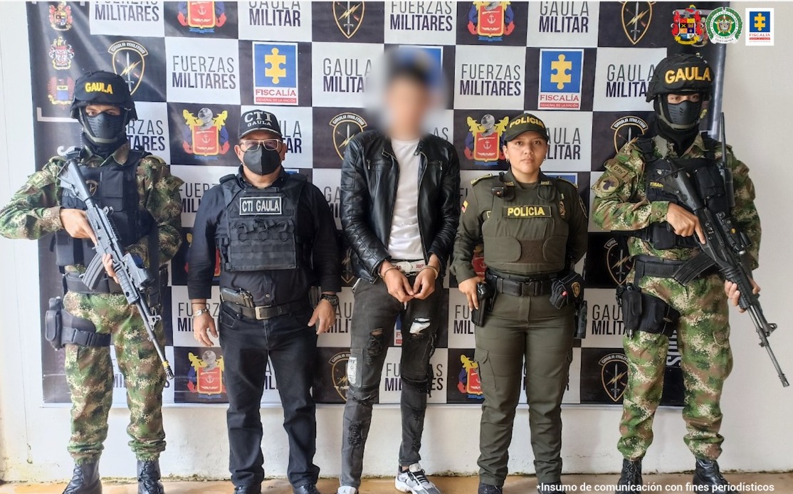 El capturado tiene chaqueta de cuero negra y pantalón del mismo color y está rodeado de efectivos del CTI de la Fiscalía, Policía, y Ejército.