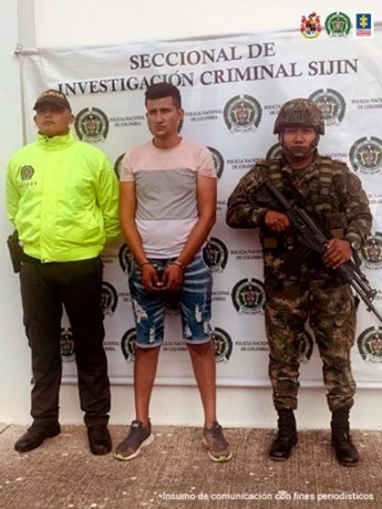 En la imagen se observa al capturado en medio de uniformados de la Policía y Ejército Nacional y en la parte posterior se observa un banner que identifica Seccional de Investigación Criminal SIJIN