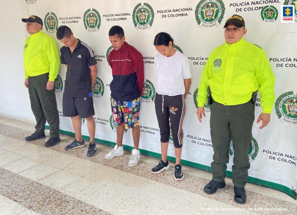 En la fotografía aparecen tres capturados, junto a personal de Policía Nacional. En la parte posterior de la imagen se ven banners de Policía Nacional y la Fiscalía General de la Nación. 