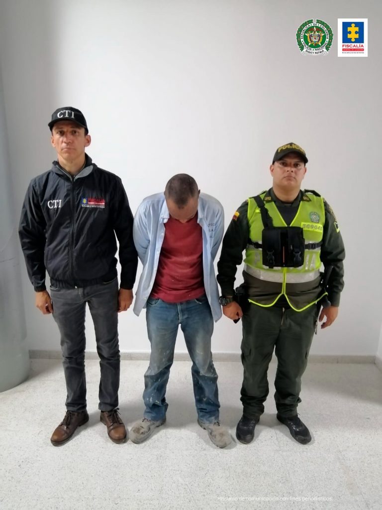 en la imagen se ve una persona detenida bajo custodia de integrantes de la Policía Nacional y el CTI.