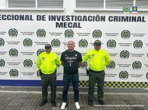 En la fotografía se aprecia de pie, cabeza rapada y con los brazos atrás a Jhon Fredy Ávila Giraldo. Viste Camiseta negra de manga corta con estampados blancos a la altura del pecho, entre ellas la palabra ‘Memphis’; jean azul y zapatillas blancas. A los extremos de ellos uniformados de la Policía Nacional. Detrás de ellos hay un pendón institucional de la Policía.--