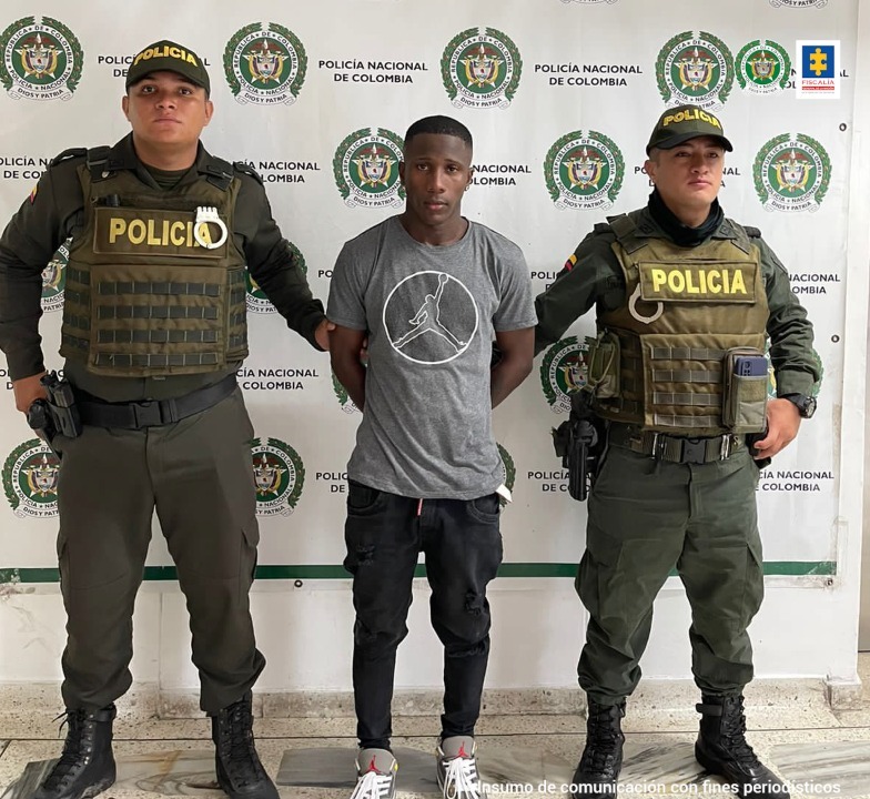 En la fotografía aparece el capturado junto a dos agentes de la Policía. En la parte posterior se ve un banner de la Policía Nacional