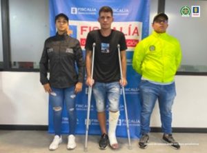 En la fotografía se observa al capturado junto a una investigadora del CTI y un integrante de la SIJIN. En la parte posterior el banner que identifica a la Fiscalía General de la Nación
