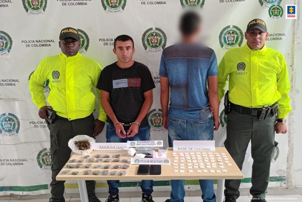 En la foto aparece de pie Joao Sergio Triviño García, alias ‘Cafir’. A su lado derecho e izquierdo hay un uniformado de la Policía Nacional. Delante de ellos hay una mesa y sobre ella hay letreros y elementos como marihuana, celulares, base de cocaína y otros elementos. Detrás de ellos hay un pendón institucional de la Policía.