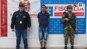 En la fotografía aparece un capturado, junto a personal de Ejército Nacional y Fiscalía General de La Nación. En la parte posterior de la imagen se ven banners de Ejército Nacional y la Fiscalía General de la Nación.      