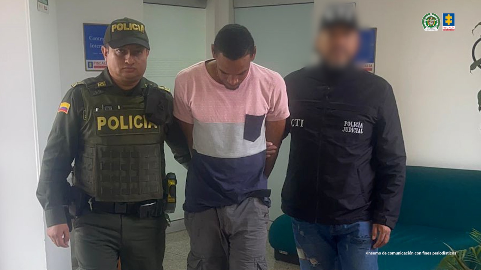 En la fotografía, tomada en un pasillo, se aprecia en acción de caminata, con la cabeza agachada y los brazos atrás a Jhoann David Rodríguez Estupiñán. Viste camiseta de manga corta en tres colores distribuidos de arriba abajo así: rosado, gris claro y azul; asimismo, pantalón gris con bolsillos. Al lado izquierdo hay un servidor del CTI de la Fiscalía y al derecho un uniformado de la Policía.
