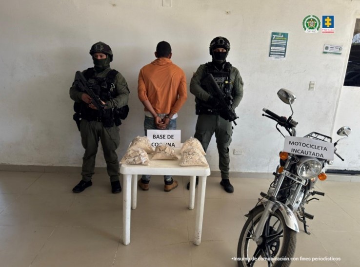 Se visualiza al capturado de espaldas, junto a dos uniformados de la Policía Nacional. Frente a ellos una mesa con la sustancia incautada.