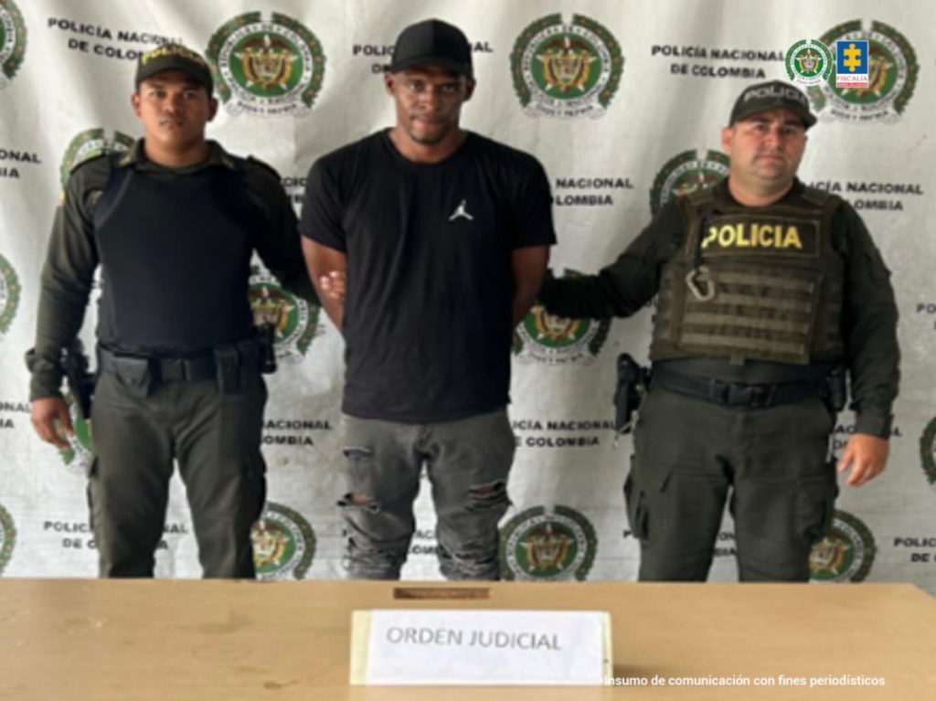 En la fotografía se aprecia de pie y con los brazos atrás a Jonatan Rentería Camacho, alias Macancan. Viste camisa de color negro y mangas cortas; jean de color gris desgastado; Gorra de color negro. A sus extremos hay uniformados de la Policía Nacional. Delante de ellos hay una superficie y sobre ella hay un letrero que dice: ‘Orden judicial’. Detrás de ellos hay un pendón institucional de la Policía.