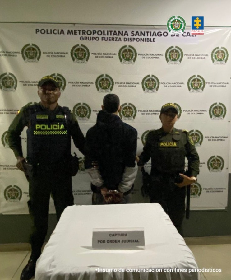 En la fotografía aparece de espaldas a la cámara, con los brazos atrás y esposado Jonathan David Nupán Ortiz. Viste con buso de color negro y mangas grises del codo hacia abajo; así como pantalón oscuro. En sus extremos hay uniformados de la Policía Nacional. En la parte delantera hay una superficie con mantel blanco y sobre ella hay un letrero que dice: ‘Captura por orden judicial’. En la parte posterior hay un pendón institucional de la Policía.