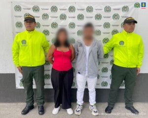 Los imputados se encuentran custodiados por dos uniformados de la Policía Nacional. Los capturados tienen cubierto el rostro. Detrás se observa un backing de la Policía.