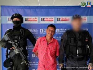 En la imagen está capturado con un servidor del CTI y otro de la Policía Nacional a los lados, y atrás un pendón azul de la Fiscalía General de la Nación