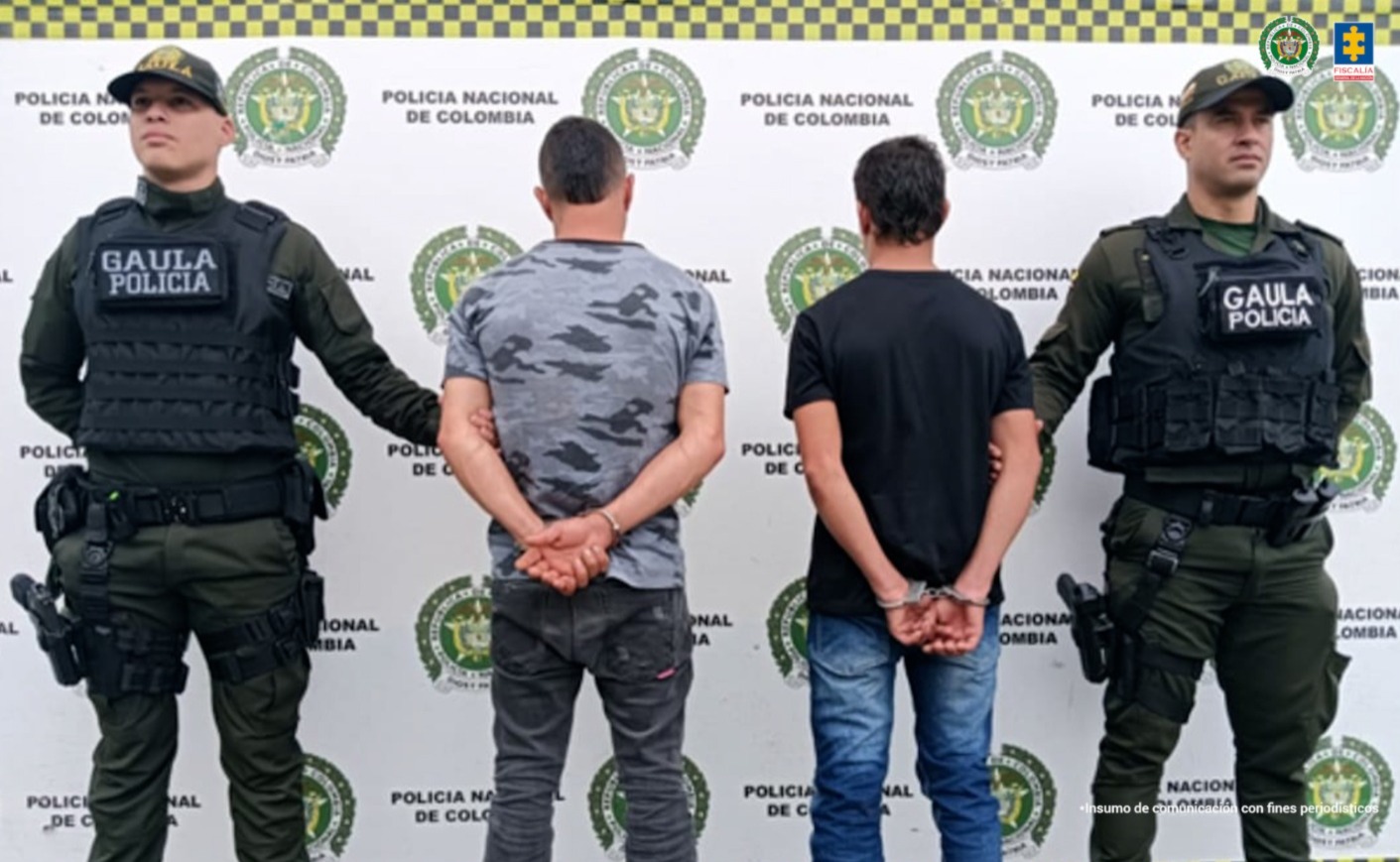 En la fotografía se aprecia de espaldas a la cámara, con los brazos atrás y esposados a Jorge Luis Ortiz Escobar y Juan Camilo Londoño Ortiz. Uno viste camiseta gris, camuflada y de manga corta; jean gris oscuro y zapatillas negras. El otro viste camiseta de manga corta de color negro, jean azul y zapatillas negras con blanco. A sus extremos hay uniformados de la Policía Nacional y en la parte posterior hay un pendón institucional de la Policía.
