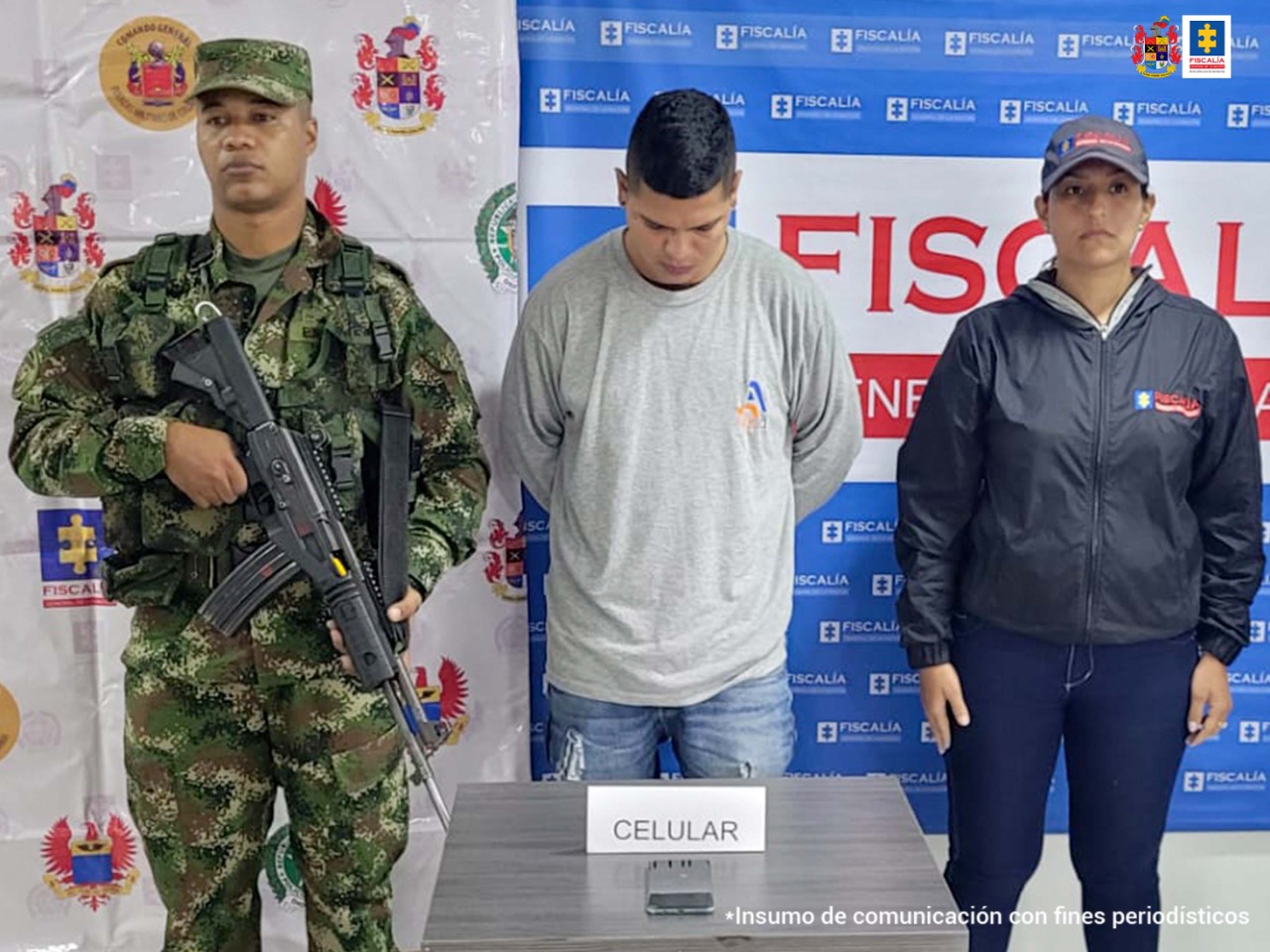En la fotografía aparece un capturado, junto a personal de Ejército Nacional y Fiscalía General de la Nación. En la parte posterior de la imagen se ven banners de Ejército Nacional y la Fiscalía General de la Nación.
