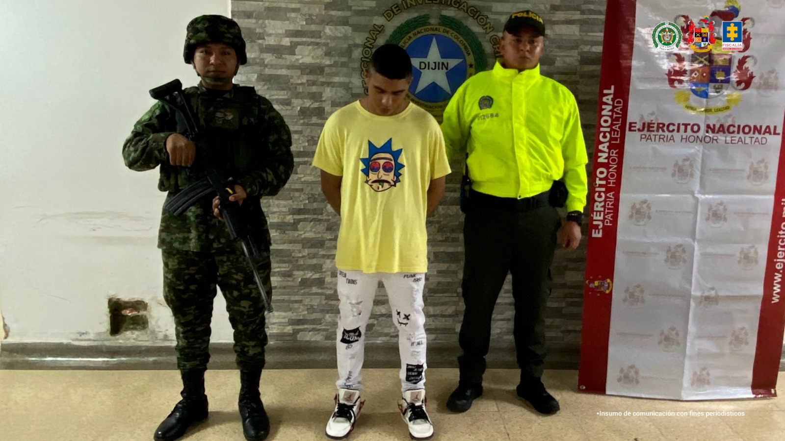 Se visualiza al capturado junto a uniformados del Ejército y la Policía Nacional. Detrás de ellos el banner que identifica a la Policía y Ejército Nacional.