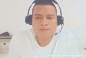 La fotografía fue tomada durante las audiencias concentradas y se aprecia a José David Zapata Ipía con cabello rapado, usando una diadema como micrófono y viste con camiseta de color blanco.