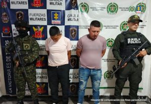 Los dos capturados se encuentran de frente y custodiados por dos uniformados del Gaula de la Policía Nacional