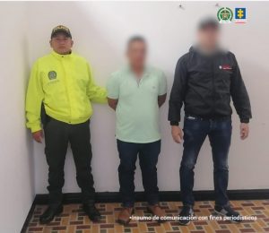El capturado se encuentra de frente y custodiado por un servidor del CTI y de la Policía Nacional.