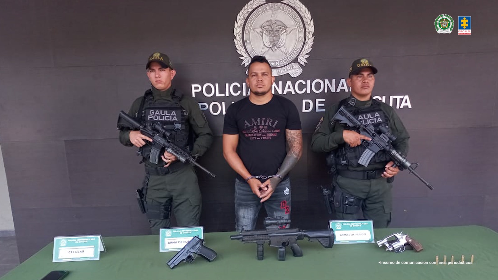 En la imagen se observa al capturado junto a dos uniformados de la Policía Nacional. Frente a ellos una mesa con los elementos incautados. Detrás el banner que identifica a la Policía Nacional.