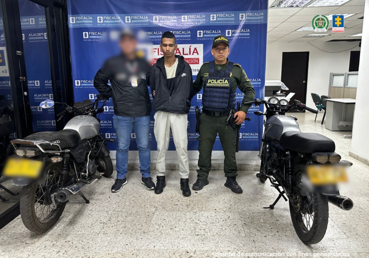 En la fotografía se aprecia de pie y con los brazos atrás a José Julián Rendón Cardona. Viste chaqueta negra y debajo de ella usa camiseta blanca con negro; pantalón blanco y zapatos negros. A su derecha hay un servidor del CTI de la Fiscalía y a la Izquierda hay un uniformado de la Policía Nacional. A los extremos hay dos motocicletas. Detrás de ellos hay un pendón institucional de la Fiscalía.