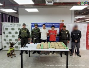 Se visualiza a los capturados junto a un investigador del CTI y uniformados del Ejército y Policía Nacional. Frente a ellos los elementos incautados. Detrás de ellos los banners que identifican a la Fiscalía General de la Nación y del Ejército y Policía Nacional.