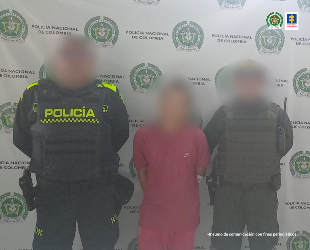 En la imagen se ve una persona de suéter rojo entre dos uniformados de la Policía.