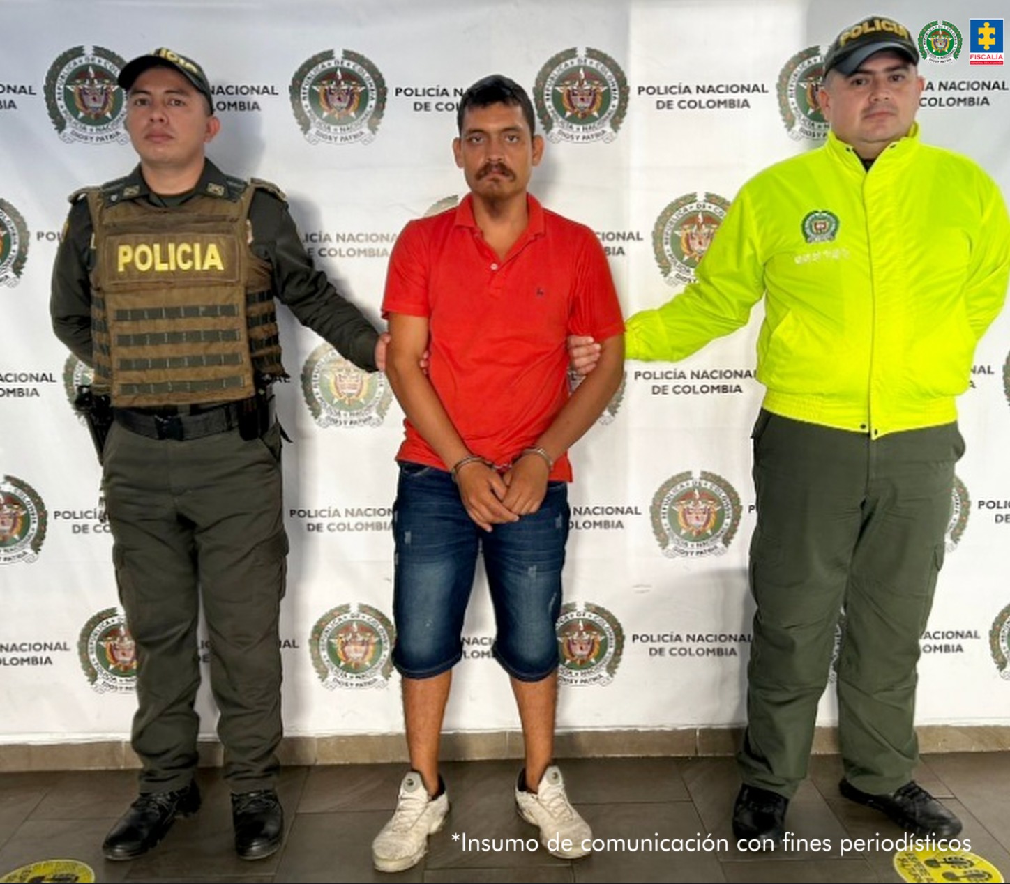 en la imagen se ve una persona detenida bajo custodia de dos integrantes de la Policía Nacional.