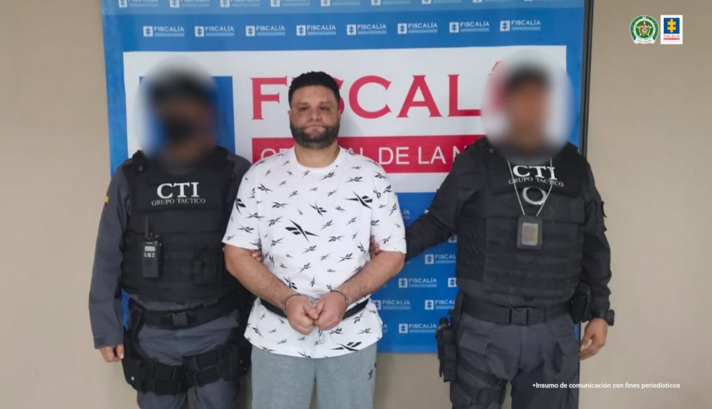 En la fotografía está Juan Camilo Vergara Uribe, alias Confite, y dos servidores del CTI a sus lados, con un pendón azul de la Fiscalía General de la Nación