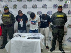 En la imagen están los 3 procesados con servidores de la Policía Nacional y los elementos incautados en una mesa. 
